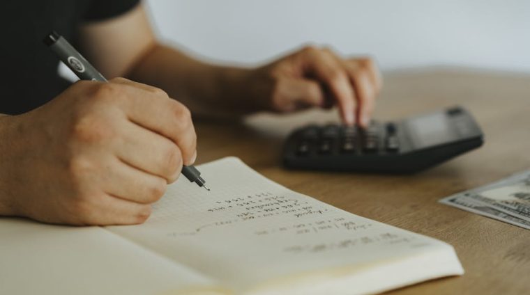 A Person Writing on White Notebook