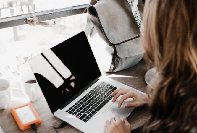 Close-up Photography of Woman Sitting Beside Table While Using Macbook