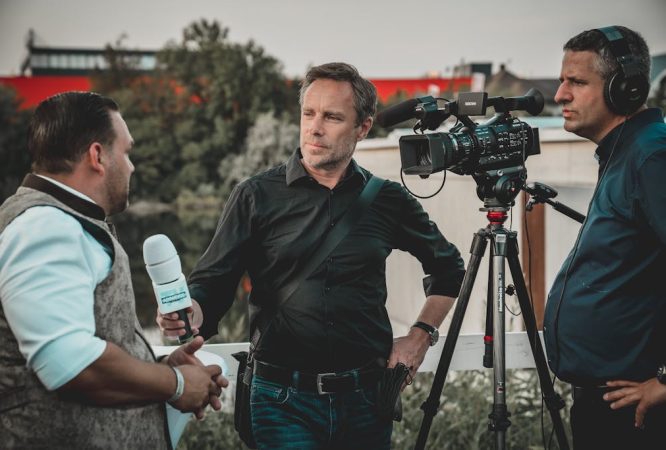 Man Holding Microphone While Talking to Another Man