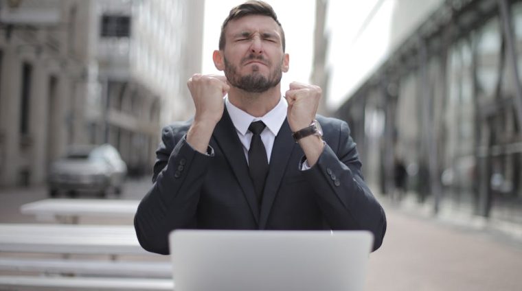 Man in Black Suit Sitting on Chair Beside Buildings