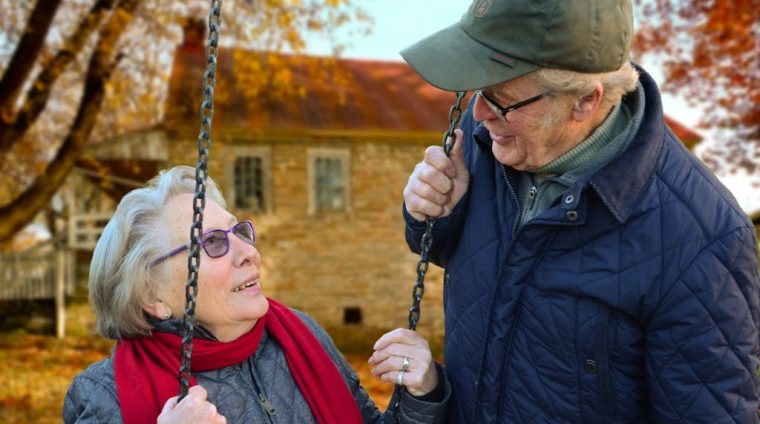 Man Standing Beside Woman on Swing