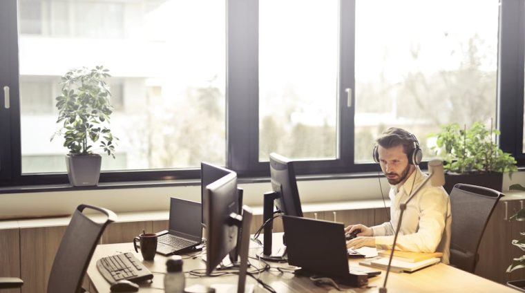 Man With Headphones Facing Computer Monitor