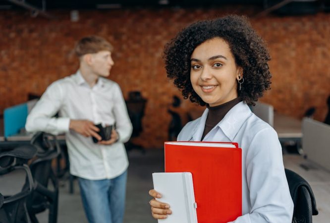 Young Woman in White Long Sleeve Shirt Holding Financial Book Report and Standing with Her Colleagues Inside an Office